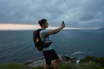 Vista laterale viaggiatore maschile scattare foto del cielo su smartphone in estate — Foto stock