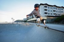 De dessus de adolescent garçon montrant cascade sur skateboard tout en pratiquant sur la rampe et en sautant dans skate park — Photo de stock