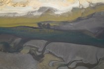 Von oben strömt graues Wasser oder Fluss und bildet ungleichmäßige abstrakte Ornamente auf unwegsamem Gelände in Island — Stockfoto