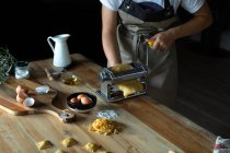 Pessoa irreconhecível preparando raviolis e massas em casa. Ela está usando uma máquina de massas — Fotografia de Stock