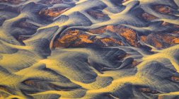 Vista aérea desde arriba del río con agua anaranjada que fluye a través de un campo accidentado en Islandia - foto de stock