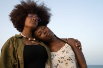 Glückliche junge afroamerikanische Freundinnen umarmen sich, während sie gemeinsam den Sommerurlaub am Meer verbringen — Stockfoto