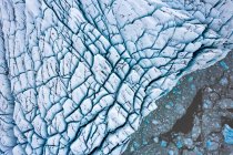 Сверху беспилотник видит льдины, плавающие в холодной морской воде около грубого ледника зимой в Исландии — стоковое фото