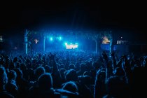 Danse de foule dans la salle de concert moderne aux néons bleus lors d'un spectacle musical en direct — Photo de stock