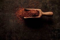 Vue de dessus de la cuillère en bois remplie de poudre de tomate séchée au soleil aromatique naturel sur fond noir — Photo de stock