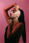 Portrait latéral de femme barbu transgenre glamour dans un maquillage sophistiqué posant les yeux fermés sur fond rose au studio — Photo de stock