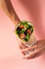 Ritagliato mani persona irriconoscibile che tengono vegan falafel avvolgere su sfondo rosa colorato — Foto stock