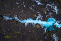 Vue au-dessus du drone du pont traversant un ruisseau rapide avec de l'eau bleue en terrain accidenté en Islande — Photo de stock