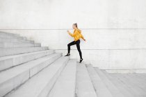 Junge athletische kaukasische Frau mit Kopfhörern und Sportkleidung, die im Freien Treppen rennt — Stockfoto