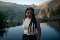 Afroamerikanerin mit Flechtfrisur steht gegen Swimmingpool in Ferienort im Hochland — Stockfoto