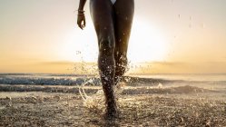 Кроп черная женщина с косичками работает на пляже — стоковое фото