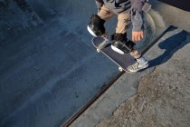 Сверху анонимный мужчина-фигурист, стоящий со скейтбордом на рампе скейт-парка — стоковое фото