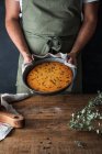 Обрізаний анонімний чоловічий кухар тримає тарілку зі смачним гарбузовим пирогом на пиломатеріалі — стокове фото
