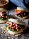 Harmful lush wheat bao buns with fresh vegetables and juicy meat on wooden table — Stock Photo