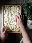 Вид зверху на безлику людину, яка готує сире тісто для хліба, розміщеного на папері для випічки на столі — стокове фото