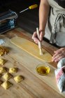 Невпізнавана людина готує равіолі та макарони вдома. Вона малює макарони з яйцями — стокове фото