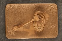 Top view of gold fork placed near sealed canned food on rectangular copper tray — Stock Photo