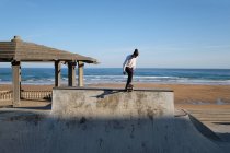 Irriconoscibile teen boy a cavallo skateboard in skate park nella giornata di sole in riva al mare — Foto stock
