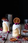 Diversi deliziosi kulichs fatti in casa versati con glassa dolce e decorati con pezzi di arancia secca e fiori sul tavolo di legno — Foto stock