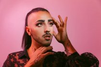 Portrait de femme barbu transgenre glamour dans un maquillage sophistiqué posant en regardant loin sur fond rose au studio — Photo de stock