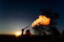 Mangiafuoco donna che esegue sputare fuoco al tramonto — Foto stock
