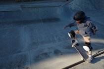 Irriconoscibile teen boy in casco protettivo guida skateboard in skate park nella giornata di sole in riva al mare — Foto stock