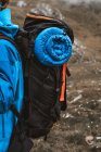 Vista laterale di tranquilla donna anonima in giacca blu brillante con zaino in piedi su una collina rocciosa — Foto stock