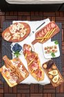 Table installée sur une terrasse avec divers délicieux apéritifs tels que jambon serrano, brochettes marinées, noix, etc. — Photo de stock