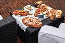 Table installée sur une terrasse avec divers délicieux apéritifs tels que jambon serrano, brochettes marinées, noix, etc. — Photo de stock
