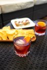 De cima de vidro com coquetel antiquado frio com gelo e fatia de laranja servida na mesa com aperitivos — Fotografia de Stock