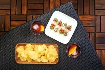 From above of glass with cold old fashioned cocktail with ice and orange slice served on table with appetizers — Stock Photo