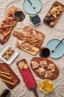 From above of assorted tasty appetizers served on table with tablecloth on terrace — Stock Photo