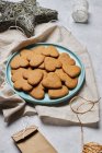 Top view of layout of sweet heart shaped Christmas biscuits on plate and assorted wrapping materials on table — Stock Photo