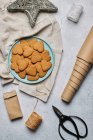 Vista dall'alto del layout di biscotti natalizi a forma di cuore dolce su piatto e materiali di imballaggio assortiti sul tavolo — Foto stock