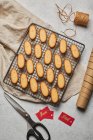 De cima de biscoitos de Natal saborosos colocados na rede de cozimento de metal na mesa com suprimentos de embalagem variados — Fotografia de Stock