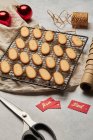 Desde arriba de sabrosas galletas de Navidad colocadas en la red de cocción de metal en la mesa con surtidos suministros de envoltura - foto de stock