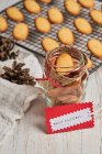 From above of tasty Christmas biscuits placed on metal baking net and glass jar on table with assorted wrapping supplies — Stock Photo