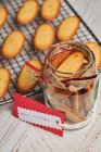 Зверху смачного різдвяного печива розміщують на металевій сітці для випічки та скляній банці на столі з різноманітними запасами для упаковки — стокове фото