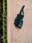 Вид зверху на повітря людини, що керує мотоциклом на сільській дорозі на сонячному світлі в сільській місцевості — стокове фото