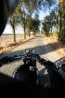 Vista trasera del corredor rápido sin rostro que monta la motocicleta a través del bosque en la ubicación rural - foto de stock