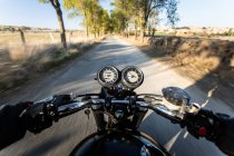 Rückansicht des gesichtslosen schnellen Rennfahrers, der Motorrad durch Wald in ländlicher Lage fährt — Stockfoto