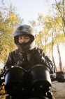 Piloto masculino envelhecido concentrado em capacete de fixação de jaqueta de couro e sentado em moto no outono dia ensolarado — Fotografia de Stock