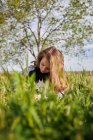 Восхитительная девочка-подросток, сидящая на лугу и рисующая в альбоме эскизов, наслаждаясь солнечным днем в сельской местности — стоковое фото