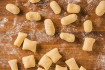 From above top view of uncooked gnocchi placed in rows on lumber table during lunch preparation at home — Stock Photo