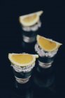 Tequila shots avec du sel et du citron placés sur une surface réfléchissante sur fond sombre — Photo de stock