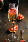 Still life composition of champagne cocktail with pomegranate on a rustic surface — Stock Photo