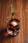 Glas Whisky mit Rosmarin auf Holztisch gestellt — Stockfoto