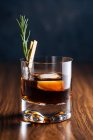 Bicchiere di whisky con rosmarino posto sul tavolo di legno — Foto stock