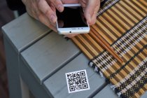 From above of crop unrecognizable male using smartphone and scanning QR code of menu of restaurant — Stock Photo