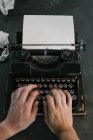 Зверху знімок рук анонімної людини, що друкує на клавіатурі старовинної друкарської машинки — стокове фото